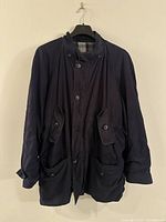 Front view of the navy blue Ermenegildo Zegna bomber jacket, showing button closure, collar, and four front pockets with button flaps.