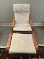 View of IKEA POÄNG bentwood frame armchair with cream cushions and footstool showing front view and cushion condition.