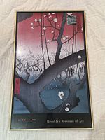 Frontal photo showing the Japanese style framed poster with blossoming tree branches by Hiroshige in a thin gold-trimmed frame and marked Brooklyn Museum of Art.