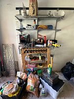 Wide view of the shelving unit and floor area with assorted garden supplies including bags, boxes, spraying equipment and more.