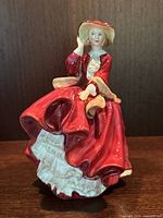 Front view of the Royal Doulton 'Top O’ The Hill' porcelain figurine showing its detailed red dress and hat.
