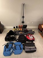 Overview of the entire lot showing skis, boots, bindings, goggles, gloves, and various bags arranged on floor.