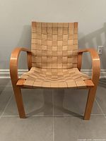 Front view of the vintage IKEA Sunne armchair showing woven seat and back with laminated beechwood curved armrests and legs.