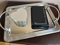 Bates Rolodex-style address book, silver plated heart-shaped jewellery box, and stainless steel tray all placed together on the tray.