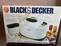 Photo of original box front showing Black & Decker branding, model B2300, breadmaker with bread pan and kneading paddle, and promotional text.