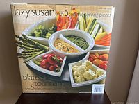 Front view of boxed ceramic Lazy Susan 5-piece serving platter set showing food on trays and product text including item number 35092