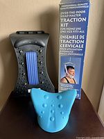Champion Plus black back stretching device with textured massage nodes and blue foam pad beside Kenko over-the-door head halter traction kit box and blue foam head halter.