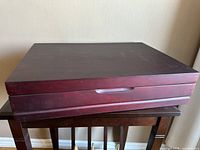 Closed cherry wooden silverware storage box showing smooth finish and handle on front