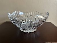 Side view of the clear crystal bowl showing the wavy rim and vertical cut pattern.