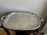 Full view of the vintage silver-plated serving tray showing overall shape, size, and floral engraved surface.