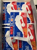 Four unopened 1989 NBA Hoops basketball card packs with blue, red, and white design showing packaging details and number of cards.