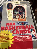 Photo showing an open box with visible Patrick Ewing and Charles Barkley cards from the 1989 NBA Hoops set.