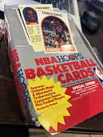 Photo of the new box of 1989 NBA Hoops Basketball Cards showing front branding and player cards for Charles Barkley and Patrick Ewing.