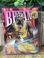 Front view of the Kobe Bryant rookie card in protective casing showing holographic background and rookie emblem.