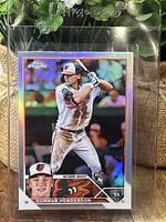 Front of 2023 Topps Chrome Gunnar Henderson refractor rookie card in protective sleeve showing player batting image with holographic colors.