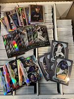 Top-down view of open storage box filled with loose cards and a spread of front-facing inserts and parallels