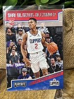 Front of Shai Gilgeous-Alexander rookie card in Clippers uniform with Playoff and Clippers logos.