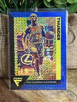 Front image of Shai Gilgeous-Alexander basketball card with holographic blue and gold patterned border and player image in Thunder uniform.