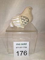 Front and side view of the hand carved dove figurine on display stand with MaxSold auction card visible.