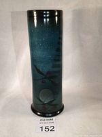 Front view of tall green cylindrical vase with abstract decoration and glossy glaze.