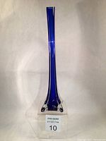Front view of the tall cobalt blue glass bud vase showing the slender neck, deep blue core, and clear glass encasement with wing-like base design.