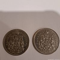 Obverse side of 1969 and 1976 Canadian 50 cent coins showing the Canadian coat of arms and denomination date.