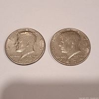 Obverse side showing the 1972 and 1974 Kennedy half dollar coins with profile of John F. Kennedy and text LIBERTY, IN GOD WE TRUST, and year.