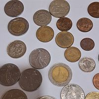 Top view of mixed foreign coins on white background showing variety of denominations and designs
