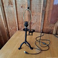 Full view of the lamp showing the black metal stand with tripod base and moose silhouette detail on the platform near the socket.