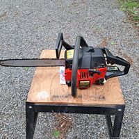 Photo showing the full Craftsman chainsaw with 16-inch bar placed on a wooden and metal stand outdoors on gravel.