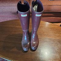 Front view of maroon Hunter rain boots showing logos and general shape.