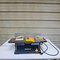 Front view of Mastercraft joiner/planer with handle guards and safety guard placed on top. Shows power switch, power cord, and Mastercraft branding.