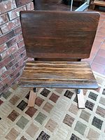 Front view of old school wooden desk chair showing contoured wooden seat and backrest.