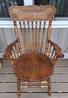 Front view of wooden captain armchair showing carved backrest, spindled back, curved armrests, and turned legs.