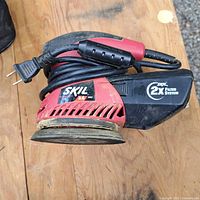 Skil orbital sander on wooden surface showing power cord and filter system label.