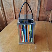 Front side showing colorful vertical stained glass strips and metal frame with attached black handle.