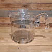Side view showing clear glass percolator coffee pot with handle and lid, minor damage on handle visible.