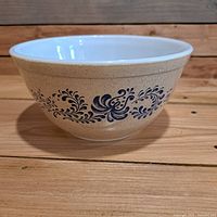 Side view of the vintage Pyrex mixing bowl showing beige speckled exterior with blue Homestead floral pattern