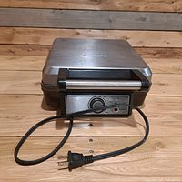 Front view of Ambiano stainless steel waffle maker with temperature control dial and power cord coiled in front.