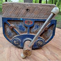 Front view of the blue cast iron vise with wooden jaws and metal handle with white plastic end caps