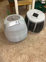 Two items on carpeted floor: Honeywell air cleaner and small electric heater side by side