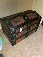 Front and top view of antique wooden humpback trunk with metal bands, star pattern on wood panels, showing wear and missing handles as per seller