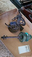 Vintage cast iron apple peeler and glass insulator placed in a cardboard box on the floor.
