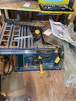 Full view of Mastercraft 10-inch bench saw with cutting table, guide components, and user manual placed around it.