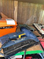 Photo showing blue Mastercraft brad nailer and orange toolbox with soldering supplies along with other tools on workbench.