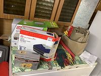 Boxed twin and queen air mattresses, Eversonic radio box, colorful blanket and soft car top carrier bag taken on table.