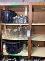 Shelf showing two black enamel canning pots and multiple glass jars of different sizes arranged on shelves.