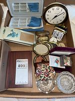 Various clocks, jewelry boxes, pin badges, coin purse, and glass ring holders arranged inside a box