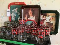 Photo showing trays and glassware from a distance to capture the entire collection including all glasses and trays with visible logos and designs.