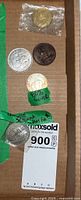 Five distinct coins and medals displayed on cardboard including one sealed in plastic and one marked 80% silver.